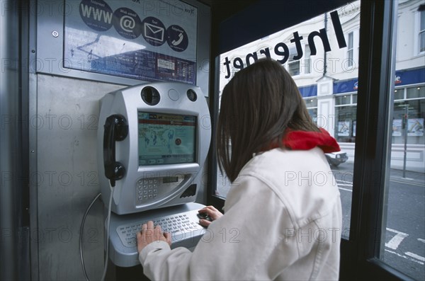 COMMUNICATIONS, Phone Box, Young woman using a public BT Internet phone booth.