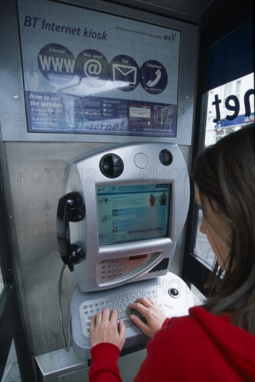 COMMUNICATIONS, Phone Box, Young woman using a public BT Internet phone booth.