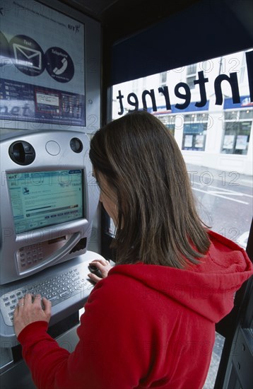 COMMUNICATIONS, Phone Box, Young woman using a public BT Internet phone booth.