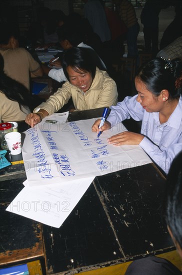 CHINA, Yunnan Province, Simao. Pu’er. Teachers sat around a table preparing a presentation on flip chat paper at a training workshop for teachers.
