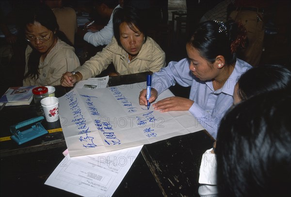 CHINA, Yunnan Province, Simao. Pu’er. Teachers sat around a table preparing a presentation on flip chat paper at a training workshop for teachers.