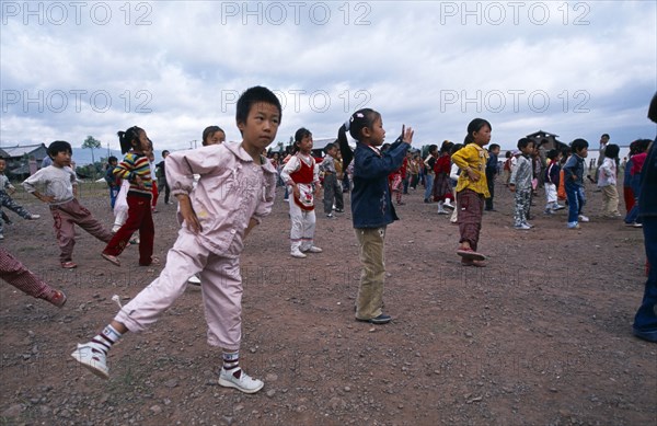 CHINA, Yunnan Province, Children taking in part in formation exercising outside of their school.