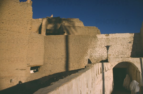 LIBYA, Ghadames Oasis, Veiled women walking through passage below mud brick town walls