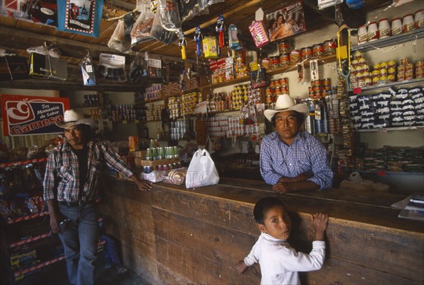 MEXICO, Chihuahua, Cusarare, Tarahumara Indian shopkeeper and customers at wooden counter inside general stores.