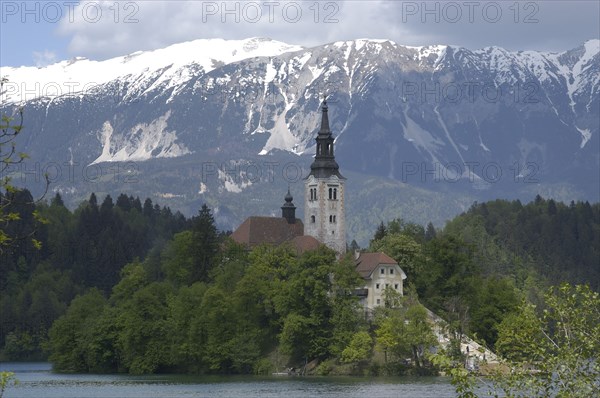 SLOVENIA, Lake Bled, View over the lake toward Bled Island and the Church of the Assumption with the snow capped peaks of the Julian Alps behind