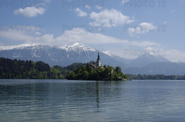 SLOVENIA, Lake Bled, View over the lake toward Bled Island and tower of the Church of the Assumption with snow capped peaks of the Julian Alps behind