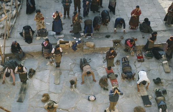 TIBET, Lhasa, Jokhang Monastery, Pilgrims prostrate themselves and pray in front of Jokhang Monastery.
