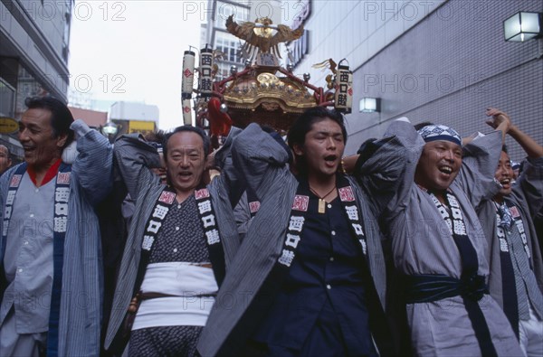 JAPAN, Honshu, Tokyo, Shinjuku. Men carrying Mikoshi throught the street during a festival celebration