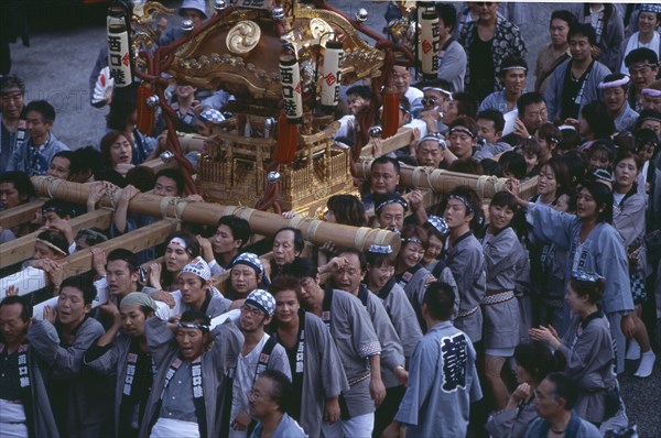 JAPAN, Honshu, Tokyo, Shinjuku. Crowd of people carrying Mikoshi throught the street during a festival celebration