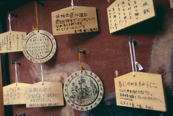 JAPAN, Honshu, Kyoto, Sanjusangen do Temple. Ema wooden votive tablets hanging from hooks on a wall