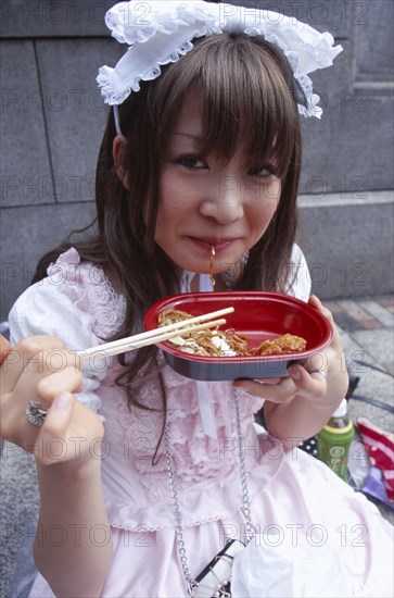 JAPAN, Honshu, Tokyo, Harajuku District. Portrait of young teenage girl eating noodles