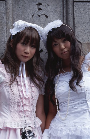 JAPAN, Honshu, Tokyo, Harajuku District. Portrait of two young teenage girls wearing pink and white dresses