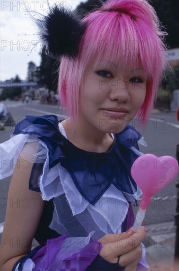 JAPAN, Honshu, Tokyo, Harajuku District. Portrait of a teenage girl with pink hair and several facial piercings