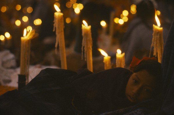 MEXICO, Festivals, Young girl holding candle lit graveside vigil for Day of the Dead. Dia de los Muertos