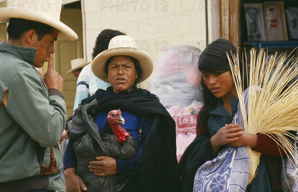 PERU, Cajamarca, Celendin, "Market scene with woman holding turkey, in conversation with man and another young woman."