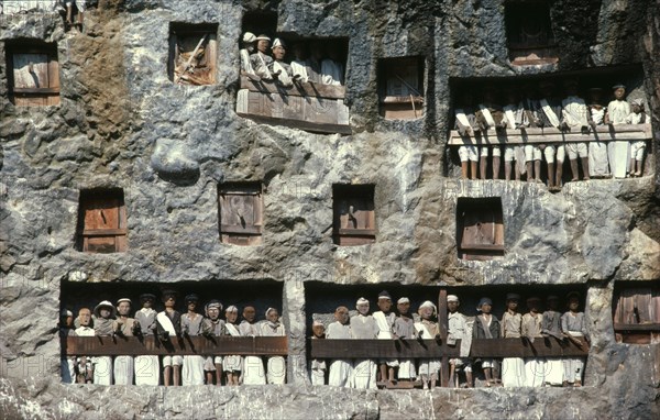 INDONESIA, Sulawesi, Toraja wooden funeral effigies or tau tau in cliff graves.  The figures accompany the dead from funeral house to burial ground and watch over both the living and dead.