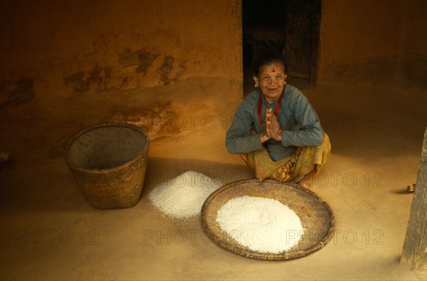 NEPAL, Chautara, Elderly woman with woven basket of grains.