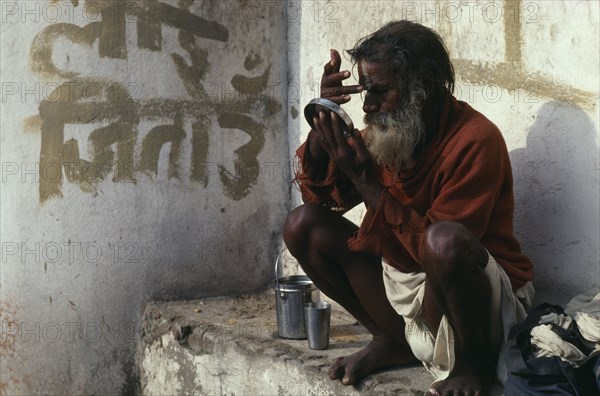 NEPAL, Kathmandu, Saddhu applying his tika mark of blessing at the Pashupatinath Temple Maha Shivaratri festival celebrating the birth of Shiva.