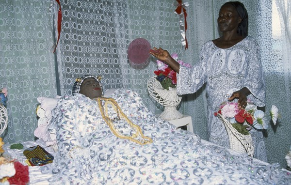 GHANA, Religion, Funeral, Deceased woman lying in state at funeral with female attendant.  This is common of Ghanaian funerals as a large wake but not usual for muslims.