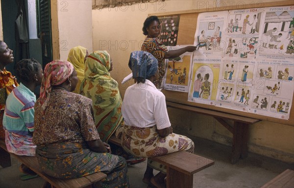 TOGO, Lome, Female teacher using story boards to demonstrate AIDS awareness and safe sex messages to group of women.