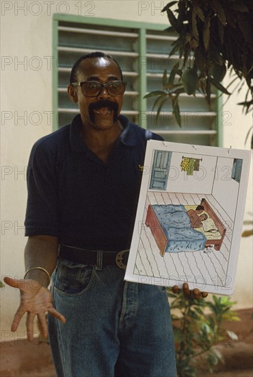 TOGO, Lome, Male teacher using story boards to demonstrate AIDS awareness and safe sex message.