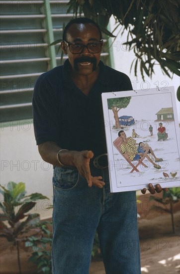 TOGO, Lome, Male teacher using story boards to demonstrate AIDS awareness and safe sex message.