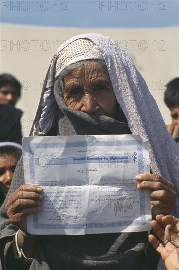 PAKISTAN, North West Frontier Province, UNHCR camp for refugees from Afghanistan.  Elderly woman holding up certificate indicating that she has received medical training.