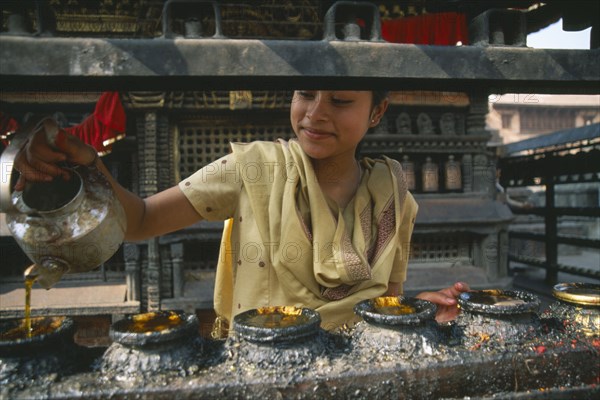 NEPAL, Swayambunath, "Young girl filling butterwick candles in shrine dedicated to Hariti, known today as Ajima in ancient temple on the outskirts of Kathmandu."