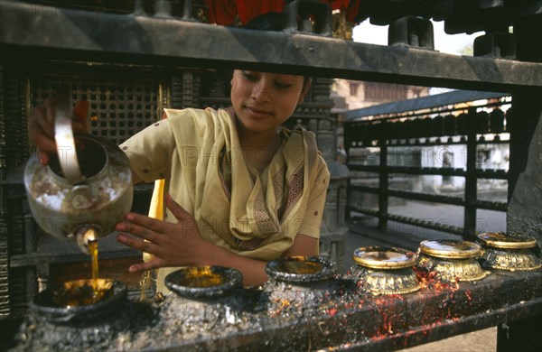 NEPAL, Swayambunath, "Young girl filling butterwick candles in shrine dedicated to Hariti, known today as Ajima in ancient temple on the outskirts of Kathmandu."