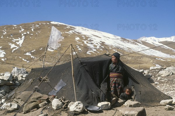 NEPAL, Mustang, Tibetan nomad woman and child looking out of tent made of yak wool on winter pasture land.