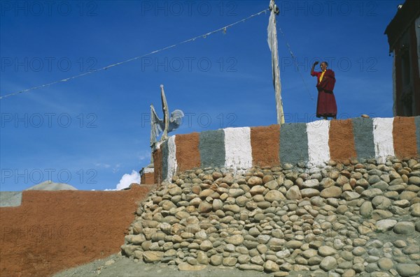 NEPAL, Mustang, Monk standing on painted terrace of Tsarang’s temple.
