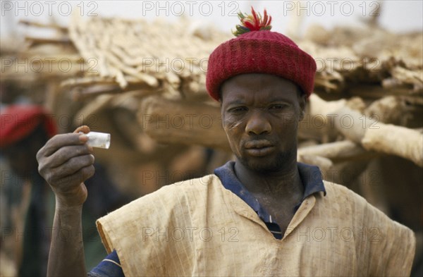 BURKINA FASO, Sahel, Miner holding up phial of gold dust.