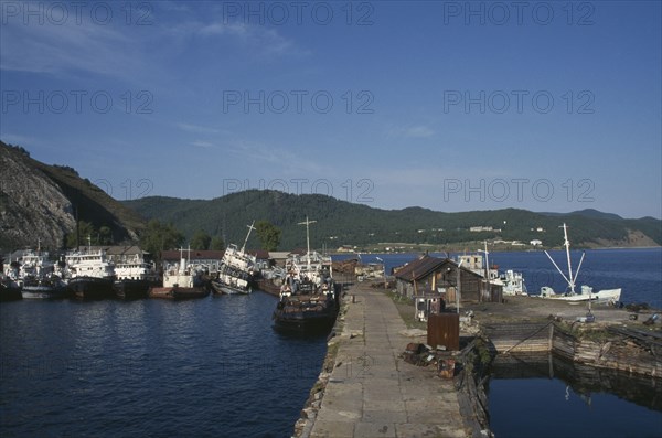 RUSSIA, Siberia, Lake Baikal, Fishing boats moored against stone jetty in lake harbour.