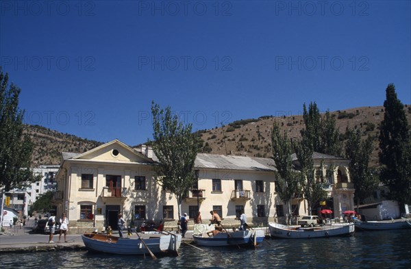 UKRAINE, Krym Republic, Balaclava, Crimean Coast.  Waterside buildings with boats moored beside quay.
