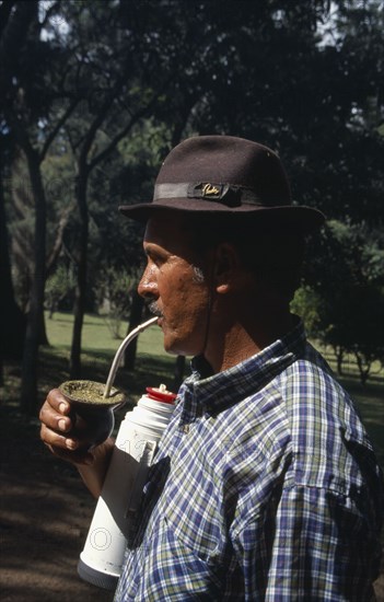 URUGUAY, Farming, Gaucho drinking mate a traditional South American herbal drink made from yerba.  The name can refer to both the drink and vessel from which it is drunk.