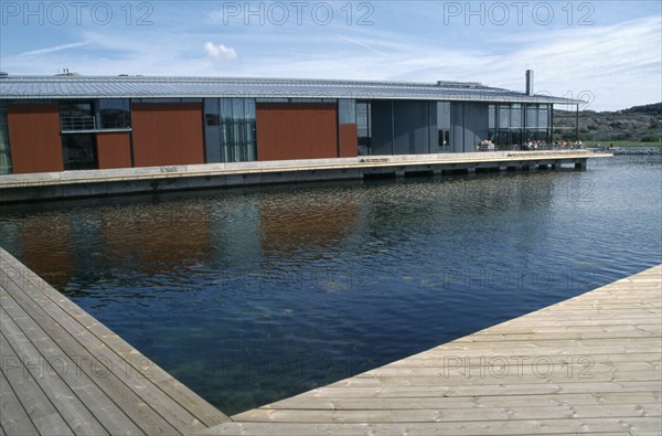 SWEDEN, Goteborg Och Bohus, Skarhamn, Water Colour Museum.  Modern building with water and wooden decking in foreground.