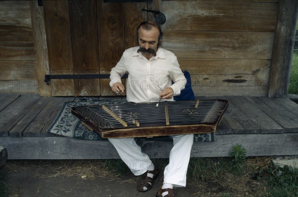 UKRAINE, Kiev, Man playing zither like instrument called a dulcimer.