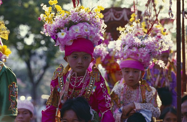 THAILAND, North, Chiang Mai, Two Luk Kaew or Crystal Children in costume carried on shoulders of adults to Shan ordination ritual at Wat Pa Pao.