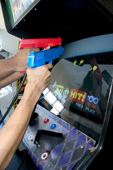 USA, Minnesota, St Paul, Teenagers shooting Point Blank video game with red and blue replica 45 caliber plastic pistols.