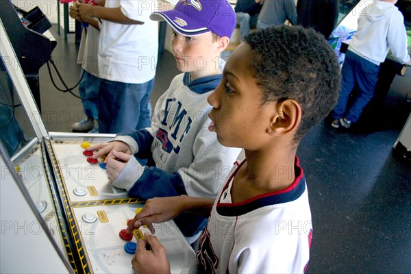 USA, Minnesota, St Paul, Friends age 10 playing video games developing their eye hand coordination at the Youth Express activity center.