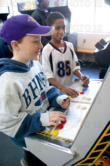 USA, Minnesota, St Paul, Friends age 10 playing video games developing their eye hand coordination at the Youth Express inner city activity center