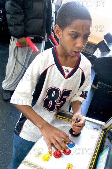 USA, Minnesota, St Paul, Young black child aged 10 playing video games developing his eye hand coordination at the Youth Express inner city activity center.