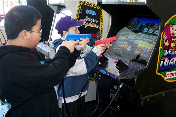 USA, Minnesota, St Paul, Kids aged 11 shooting Point Blank video game with red and blue replica 45 caliber plastic pistols.