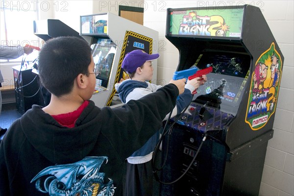 USA, Minnesota, St Paul, Kids age 11 shooting Point Blank video game with red and blue replica 45 caliber plastic pistols.