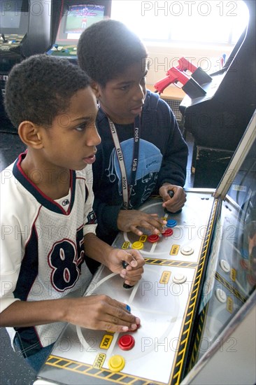 USA, Minnesota, St Paul, Friends age 11 playing video games developing their eye hand coordination at the Youth Express inner city activity center.