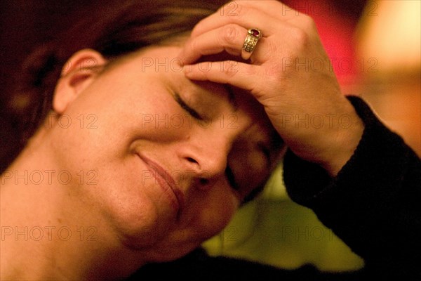 USA, Minnesota, St Paul, Woman aged 35 smiling and relaxing with her hand on her forehead and her eyes closed