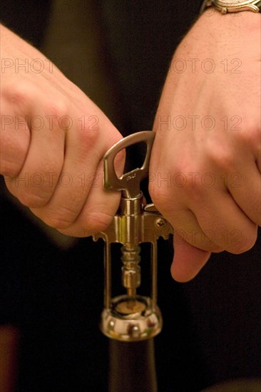 USA, Minnesota, St Paul, Opening a bottle of wine with a corkscrew.