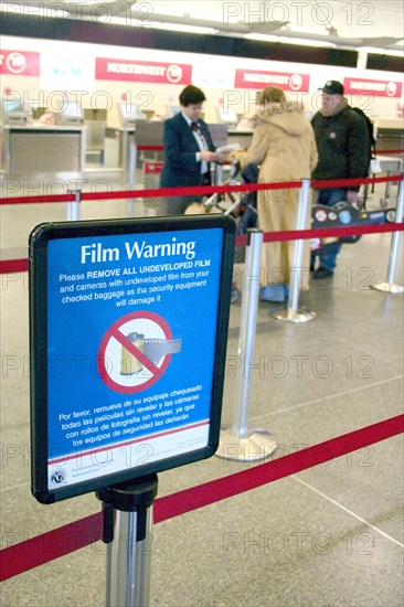 USA, Minnesota, Minneapolis, Northwest Airlines security ticket screener at Minneapolis-St. Paul International Airport Charles Lindbergh Terminal and sign warning not to send film through security equipment.