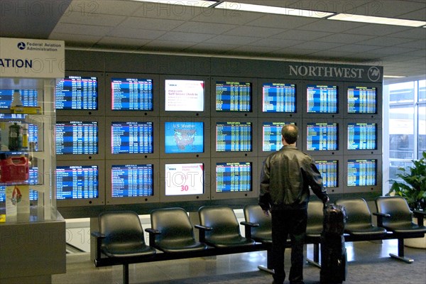 USA, Minnesota, Minneapolis, Traveller checking Northwest Airlines departure and arrival information screens at the Minneapolis-St. Paul International Airport Charles Lindbergh Terminal