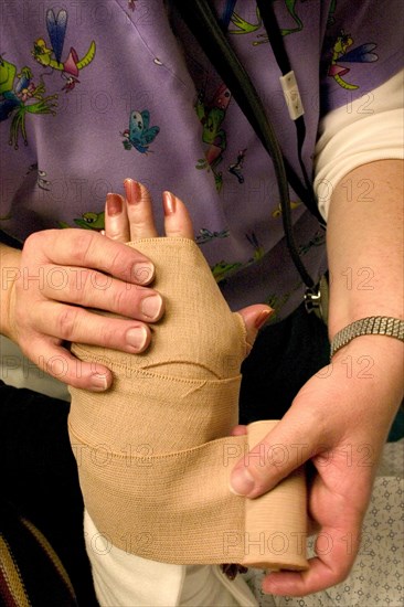 USA, Minnesota, Plymouth, Emergency room nurse wrapping temporary elastic bandage on broken wrist.